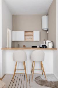 a kitchen with two white chairs and a counter at Charmant Studio Cosy - Hyper-Centre D'Elbeuf in Elbeuf
