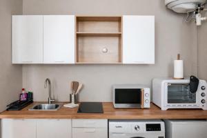 a kitchen with white cabinets and a sink and a microwave at Charmant Studio Cosy - Hyper-Centre D'Elbeuf in Elbeuf