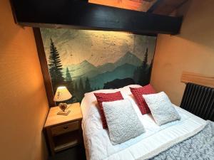 a bedroom with a bed with a painting on the wall at LA POMME DE PIN 1 Appartement avec terrasse in La Bresse