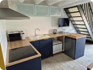 a kitchen with blue cabinets and a sink and a staircase at PLAIN PIED, avec mezzanine et espace extérieur 10min Puy du F in Les Herbiers