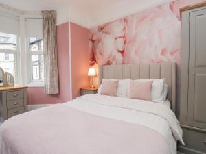 a bedroom with a white bed with a pink wall at The Wonky Nest in Windermere