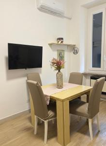 a dining room table with chairs and a vase with flowers at HOUSE Riccardo, vicino al parco Nelson Mandela in Sestri Levante