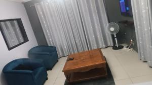 a living room with two chairs and a table and a fan at Bushman Kraal Lux in Soweto