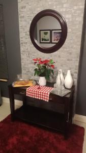 a table with a mirror and flowers on it at Bushman Kraal Lux in Soweto