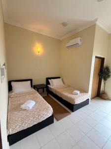 a room with two beds and a air conditioner at Summer village in Kampong Pasir Hantu