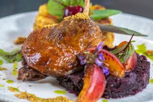 a plate of food with a piece of meat and fruit at Hotel Kiss in Tata