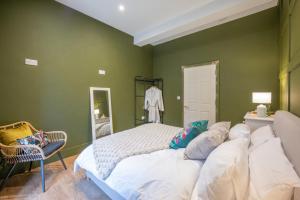 a green bedroom with a large bed and a chair at The Leiston, 1 Valley Road in Leiston