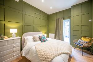 a green bedroom with a bed and a dresser and a chair at The Leiston, 1 Valley Road in Leiston