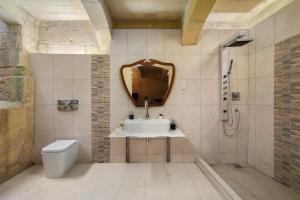 a bathroom with a sink and a toilet and a mirror at Traditional Maltese 2-Bedroom Home with Private Hot Tub - Steps Away from Valletta in Il-Furjana