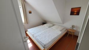 a small bedroom with a white bed in a attic at Rügennest A44 - Feriendorf Bakenberg bei Dranske in Dranske