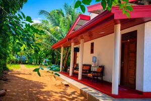 a house with a red roof and a porch at Wilpattu Gagana guest in Nochchiyagama