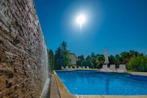 a swimming pool with a fountain next to a brick wall at Hotel Kiss in Tata