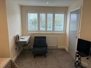 a bedroom with a desk and a chair and a bed at ROSE-WOOD Gatwick in Horley +7 photos