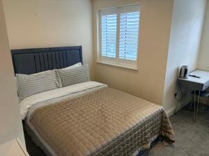a bedroom with a bed and a window and a phone at ROSE-WOOD Gatwick in Horley