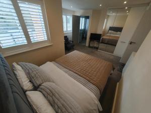 a bedroom with a bed and a couch and a mirror at ROSE-WOOD Gatwick in Horley
