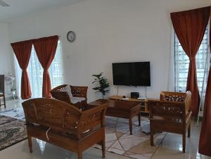 a living room with a flat screen tv and chairs at Seri Cempaka Homestay in Kluang