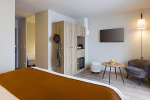 a room with a bed and a couch and a tv at SOWELL HÔTEL L'Alpe Blanche in Vars