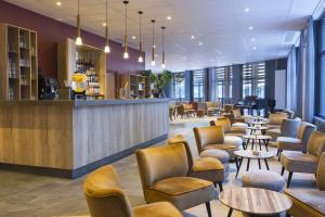 a waiting room with tables and chairs and a bar at SOWELL HÔTEL L'Alpe Blanche in Vars