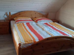 a wooden bed with two pillows on top of it at Dar Morza Domki Letniskowe in Gąski