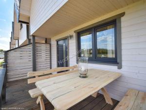 a wooden picnic table on a deck with a window at Dar Morza Domki Letniskowe in Gąski