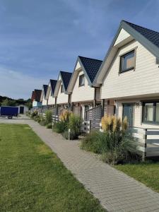 a row of houses with black roofs and a sidewalk at Dar Morza Domki Letniskowe in Gąski