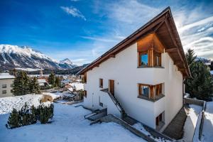 a house in the snow with mountains in the background at Chesa Sarvit in Celerina