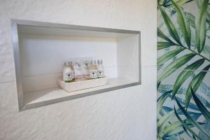 a shelf in a bathroom with bottles of soap at Topiary Lux Studio 16! in Herolds Bay