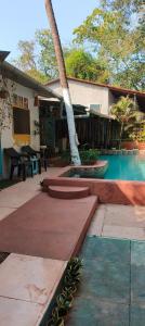a house with a swimming pool and a palm tree at Bonsaiyog in Chapora