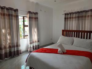 a bedroom with a bed with a red blanket and a window at Kafusi Lodge in Victoria Falls