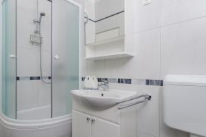 a white bathroom with a sink and a shower at Holiday Apartment Maria in Orebić