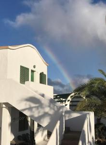 a rainbow over a white house with a palm tree at Casa Pavon in Montaña Alta