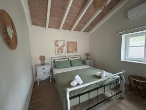 a bedroom with a bed with green sheets and a window at Loukas house Paxos in Boïkátika