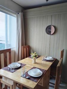 a wooden table with chairs and a clock on the wall at Coast Residences Roxas Boulevard Manila in Manila
