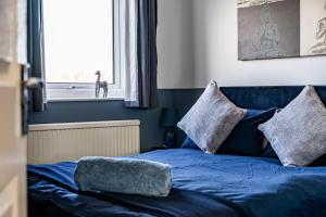 a blue bed with two pillows and a window at Comfy 3 Bed House in Northampton