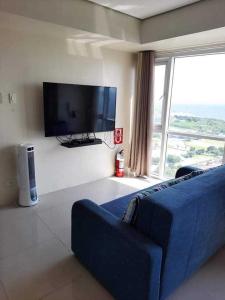 a living room with a blue couch and a flat screen tv at Coast Residences Roxas Boulevard Manila in Manila