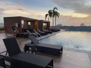 a hotel with a pool with chairs and palm trees at Coast Residences Roxas Boulevard Manila in Manila