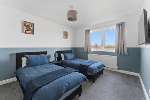 a bedroom with two beds and a window at Comfy 3 Bed House in Northampton +26 photos