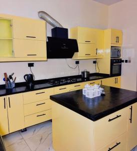a kitchen with yellow cabinets and a black counter top at Msb LUXURY HOME in Lekki