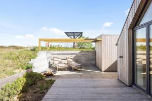 a deck with chairs and a pergola next to a house at Holiday Home Overlooking Ebeltoft Bay in Ebeltoft