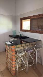 a kitchen with a counter and two stools at Quinta Di Crivelli in Praia do Rosa