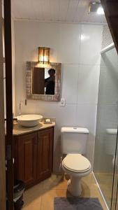a bathroom with a toilet and a sink and a mirror at Quinta Di Crivelli in Praia do Rosa