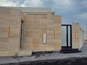 a building with a wooden wall with two doors at Al Mona Resort 2 شاليه المنى in Al Khobar