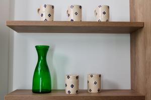 a green vase sitting on a shelf with cups at Seaside Apartments - Central Apartments with View - Molfetta in Molfetta