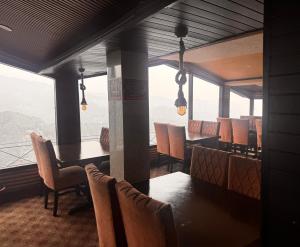 a dining room with a table and chairs and windows at mount wood heritage in Dharmsāla