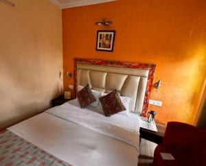 a bedroom with a white bed with an orange wall at mount wood heritage in Dharmsāla