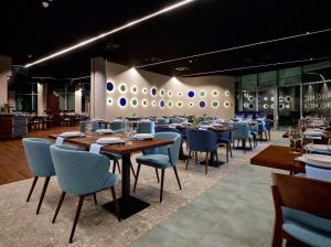 a restaurant with wooden tables and blue chairs at Hotel Verde City in Koszalin