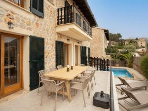 a patio with a wooden table and chairs and a pool at Casa "Valldemossa Paradise" in Valldemossa