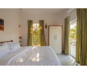 a bedroom with a bed and a large window at Casa De Alegria Goa in Canacona