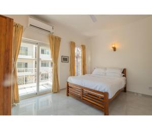 a bedroom with a bed and a large window at Casa De Alegria Goa in Canacona +2 photos