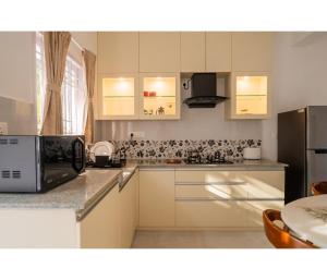 a kitchen with white cabinets and a microwave at Casa De Alegria Goa in Canacona